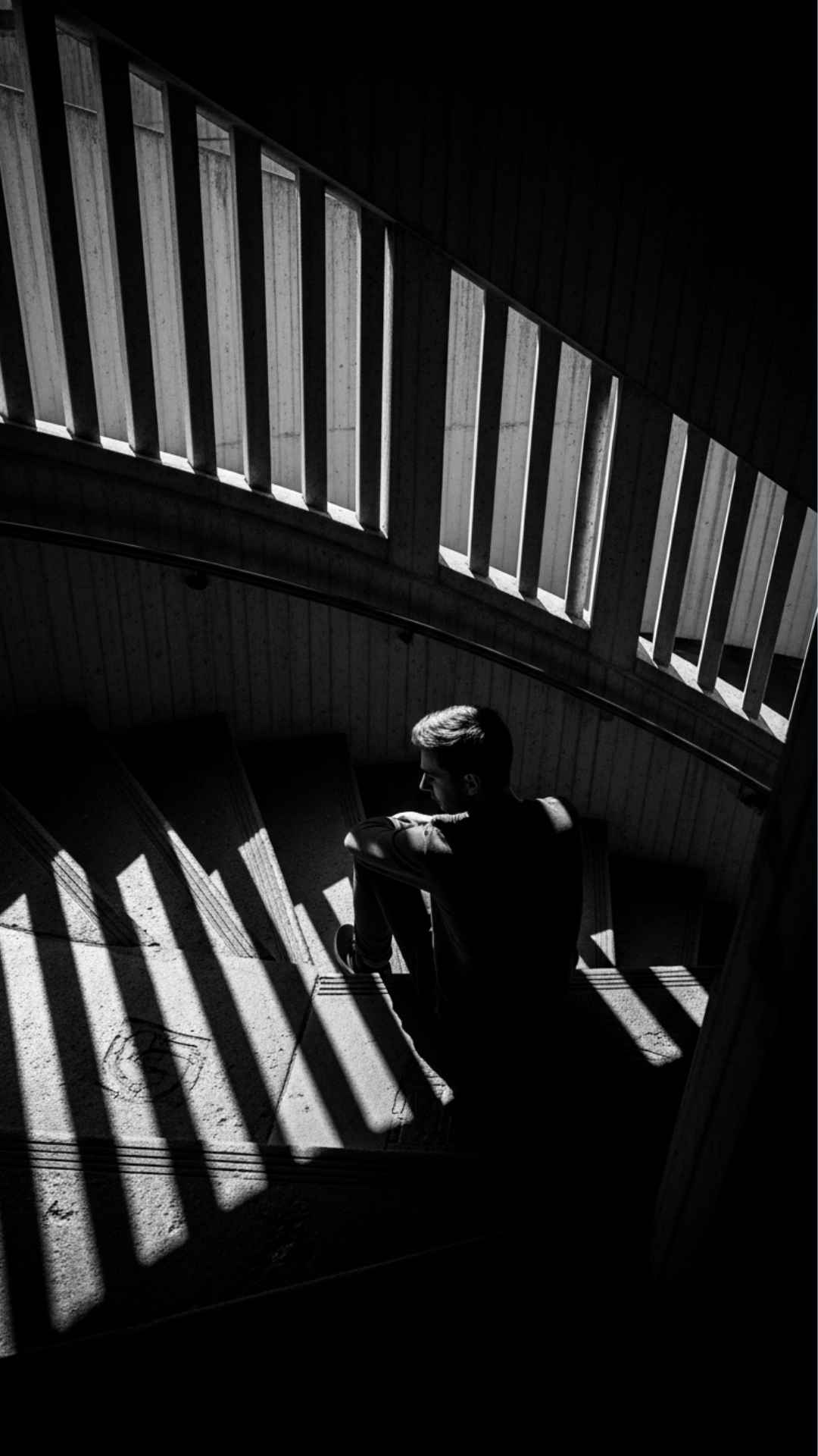 Moody black and white DP of a boy in the shadows of a spiral staircase