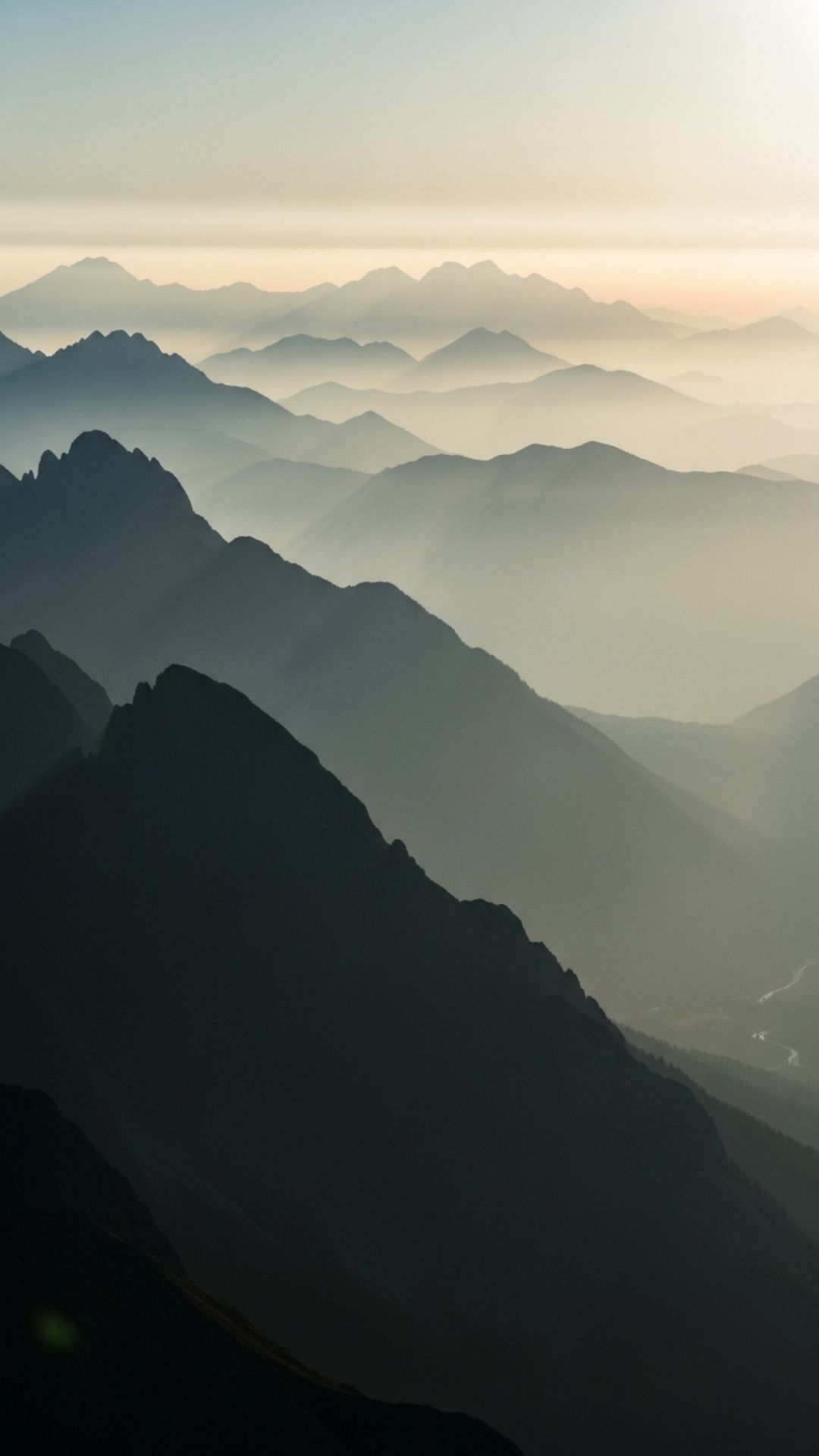 An epic 4K wallpaper of layered mountains at misty sunrise, creating a sense of depth and majesty - Mountain Wallpaper | Majekfilms.com