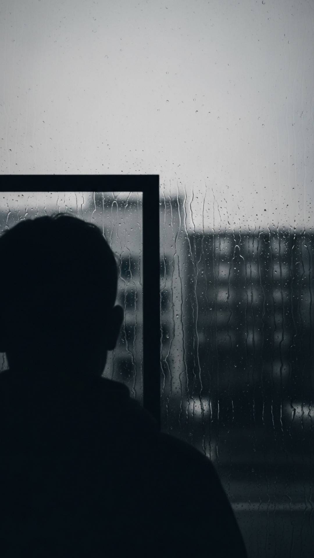 Head silhouette obscured by heavy rain on windowpane, conveying detachment and external sadness. Sad DP, rain, blurred.