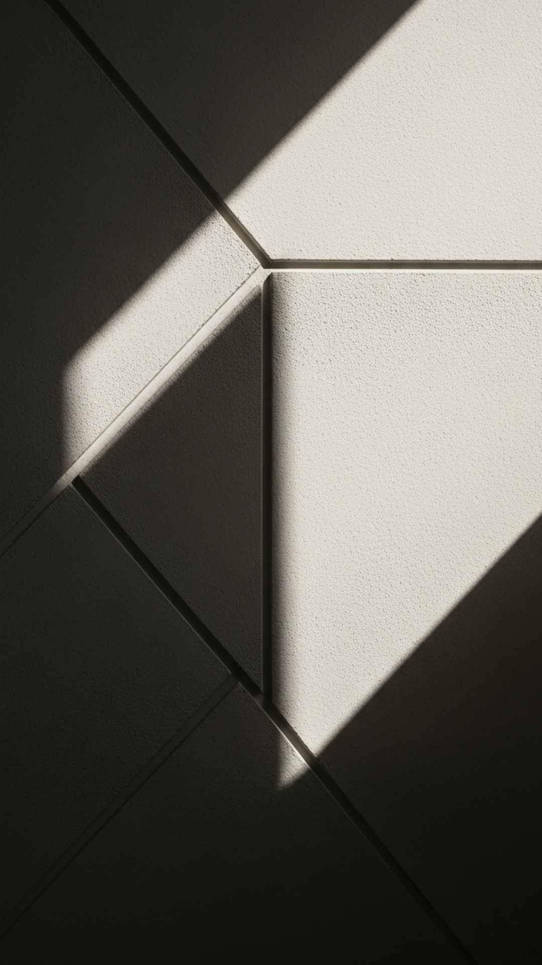 An artistic photo with abstract composition focusing on the beautiful play of light and shadows on a textured, monochrome wall, creating a sophisticated and unique aesthetic.