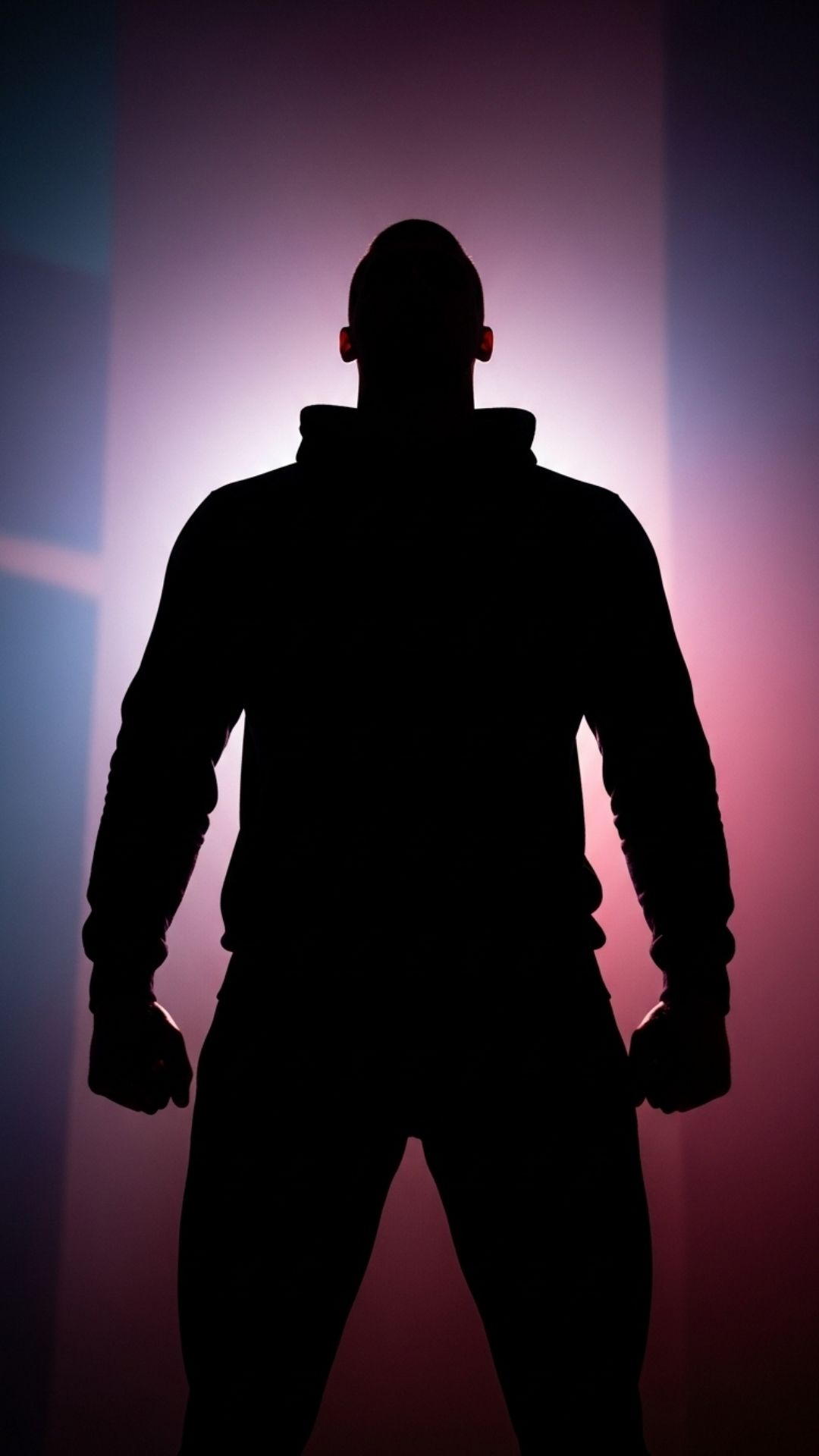 A striking male silhouette with a strong posture, illuminated by a vibrant, dramatic backlight against a blurred background.