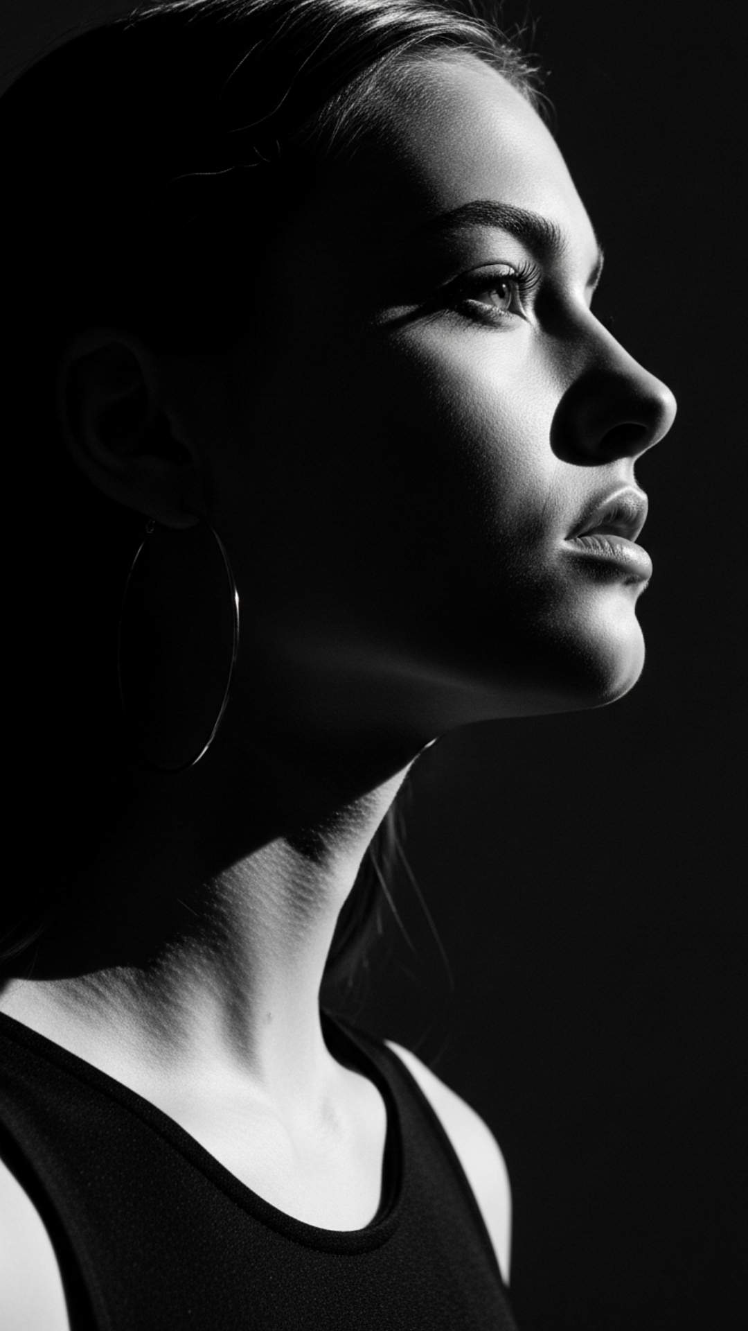 A high-contrast, black and white profile shot of a girl's face with deep shadows, conveying a strong and determined attitude.