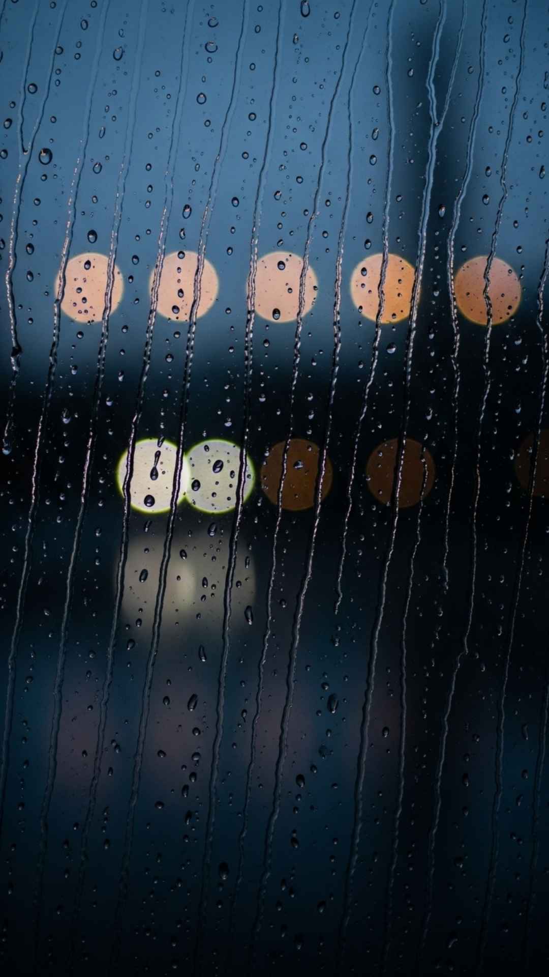 A sad black DP showing a close-up of raindrops on a window, with a blurry, lonely city in the background.