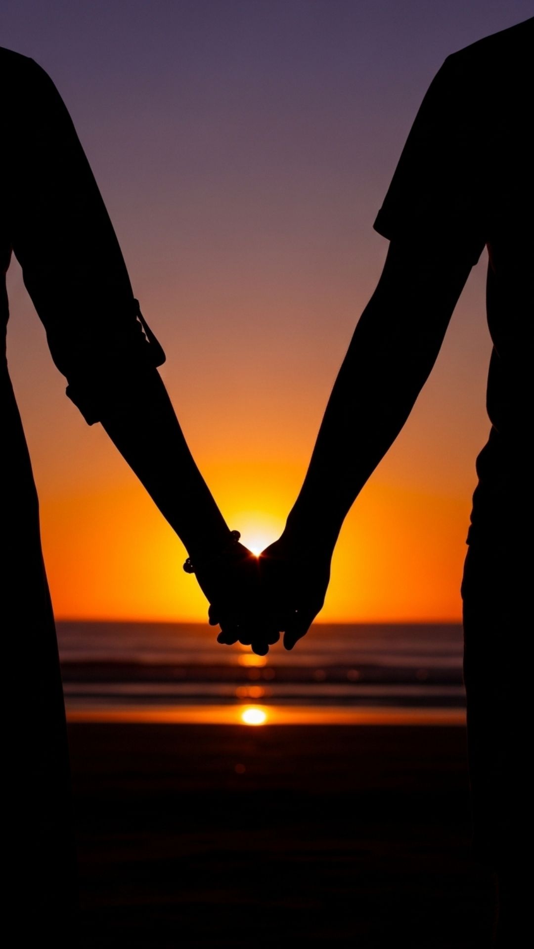 A couple's silhouette holding hands at sunset on a beach, a subtle and romantic profile picture