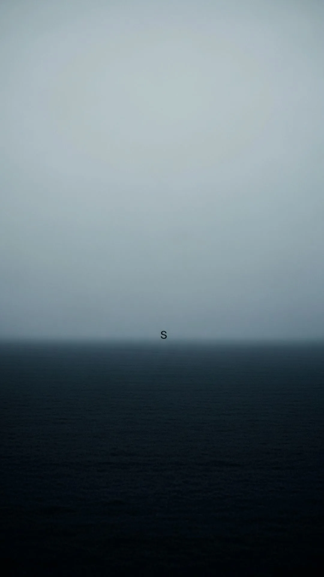 A lonely S letter DP, showing a single, small, solitary 'S' in the middle of a vast, empty, misty field at dusk. This sad S name DP perfectly expresses a feeling of being alone and emptiness, ideal for a WhatsApp profile in India. Free HD 4K download from Majekfilms.com.