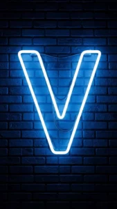 A modern 4K 'V' letter image for DP, showing a glowing 'electric blue' neon 'V' sign against a dark, wet brick wall. This 'stylish V name dp' is perfect for a cool, tech-inspired WhatsApp or Instagram profile for boys and girls in India. Keywords: neon V letter dp, V name dp stylish, V letter wallpaper aesthetic, cool V dp 4K, light V name.