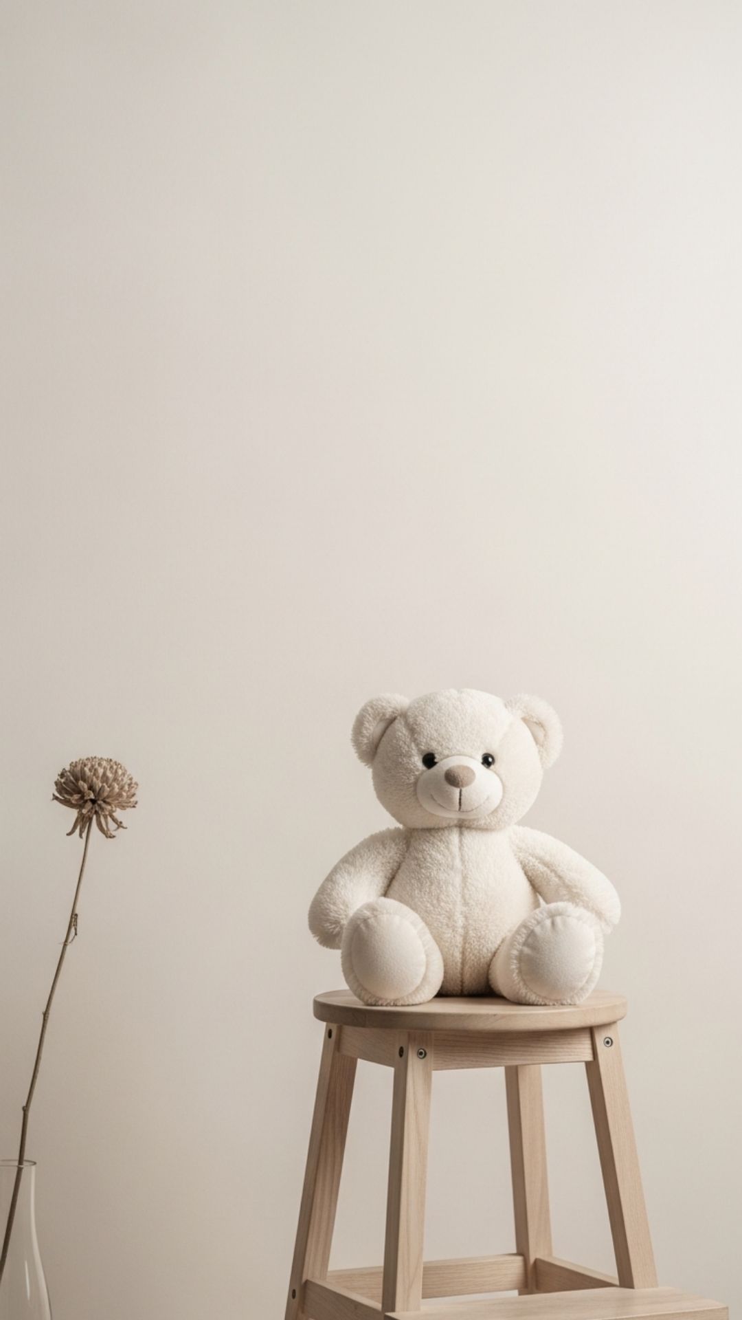 A Korean minimalist teddy bear in cream and beige tones sitting on a stool, perfect for a sophisticated and neutral Instagram profile picture or a clean aesthetic mobile wallpaper.