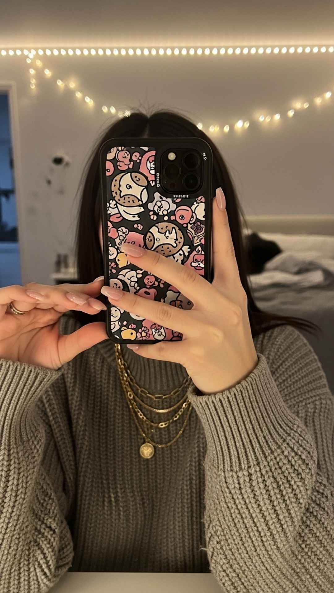 A close-up stylish mirror selfie focused on accessories and a trendy phone case while the user hides their face. This cozy, aesthetic shot is designed for camera-shy individuals who want a fashionable display picture (DP) that highlights personal style and mood without revealing facial features.
