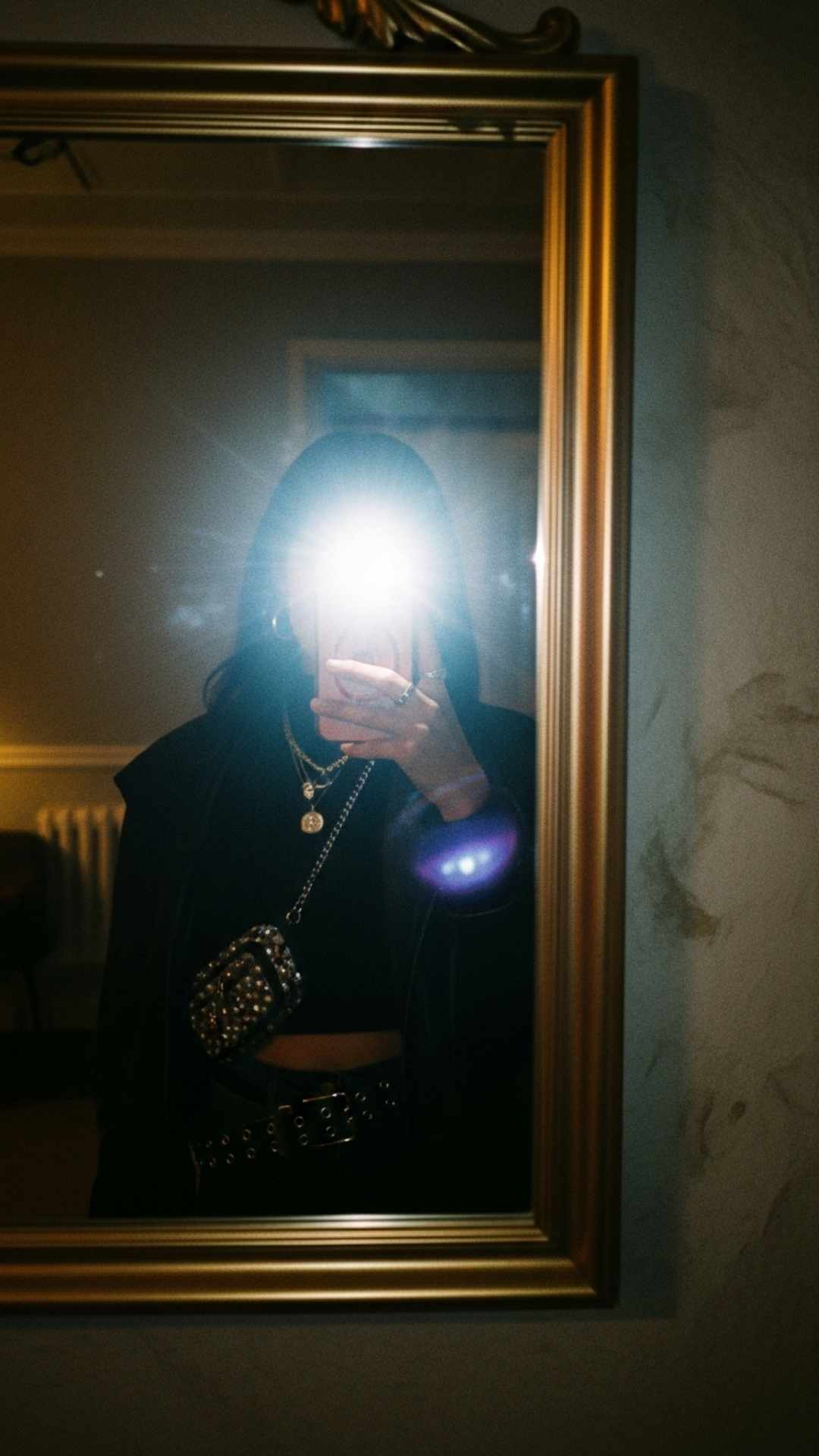 A trendy mirror selfie utilizing the "flash" aesthetic in a dark setting, creating a high-contrast, cool visual vibe. This photographic style is a popular choice for modern social media display pictures and aesthetic statements.